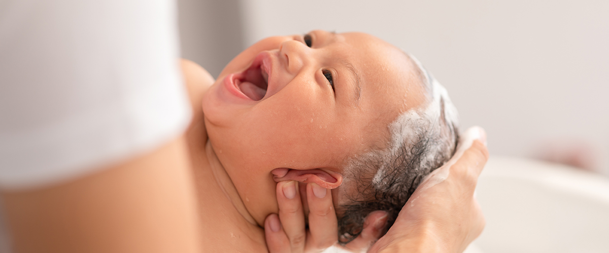 Close up newborn baby bathing in bathtub. mother bathing her son in warm water. Happy adorable newborn infant smile in tub relax and comfortable good moment with mom. Newborn baby care concept