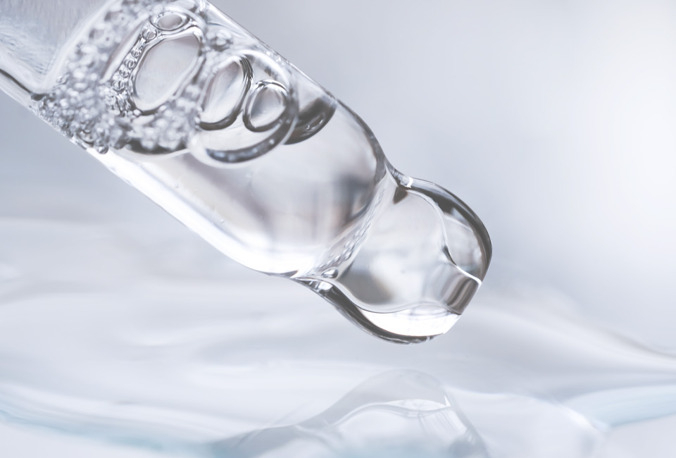 Close-up of a glass serum dropper with a clear liquid.