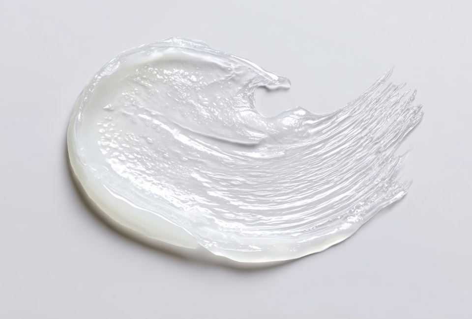 A textured smear of translucent white ointment on a plain background.